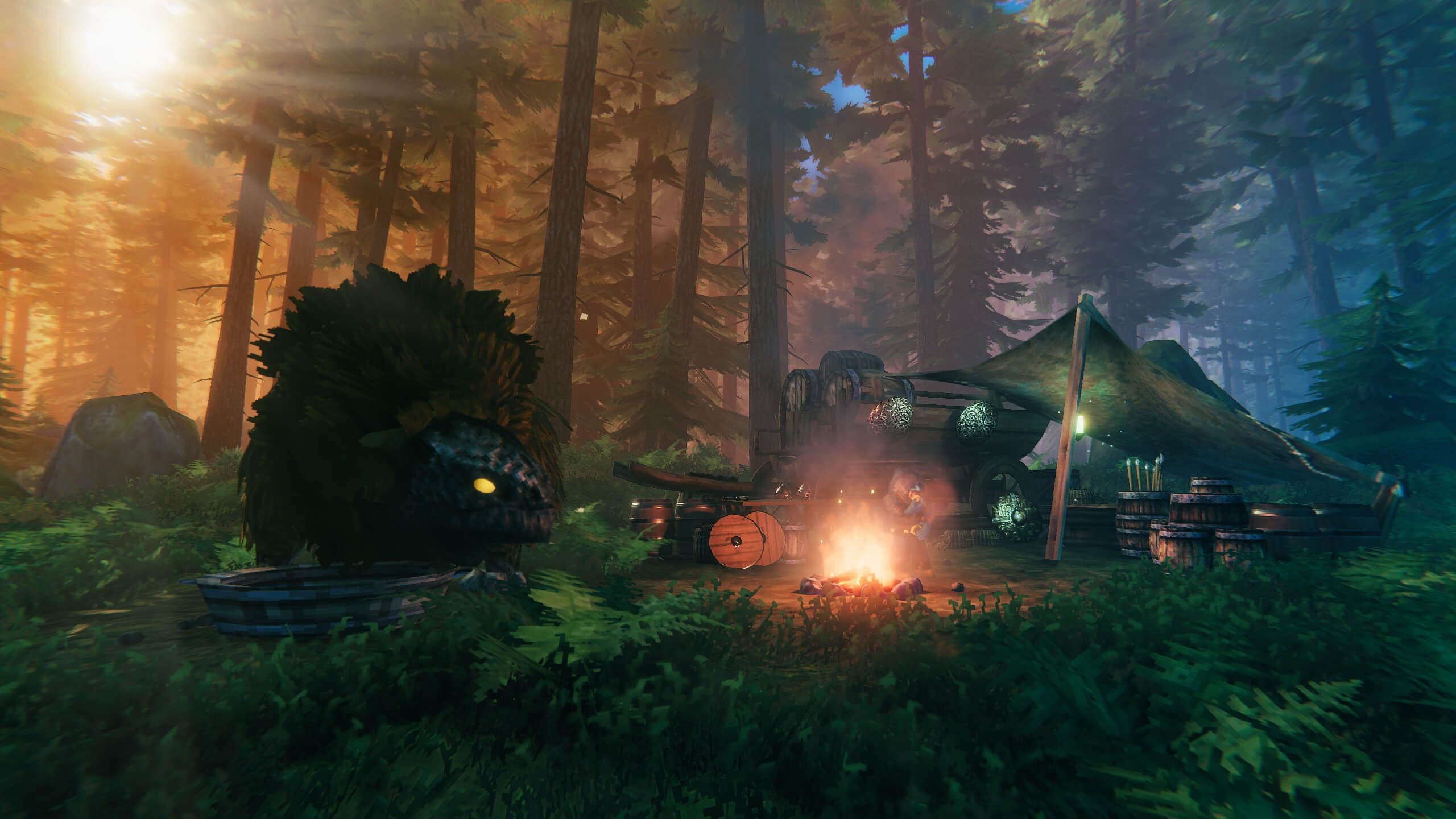 A Valheim forest camp lit by a fire, with tents, barrels, shields, and a carved boar head.